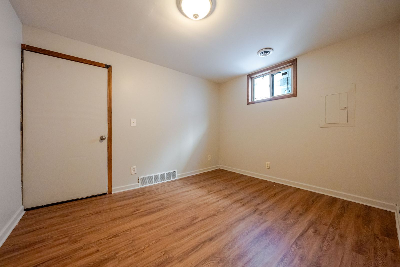 Bedroom with wood-look flooring and a small window
